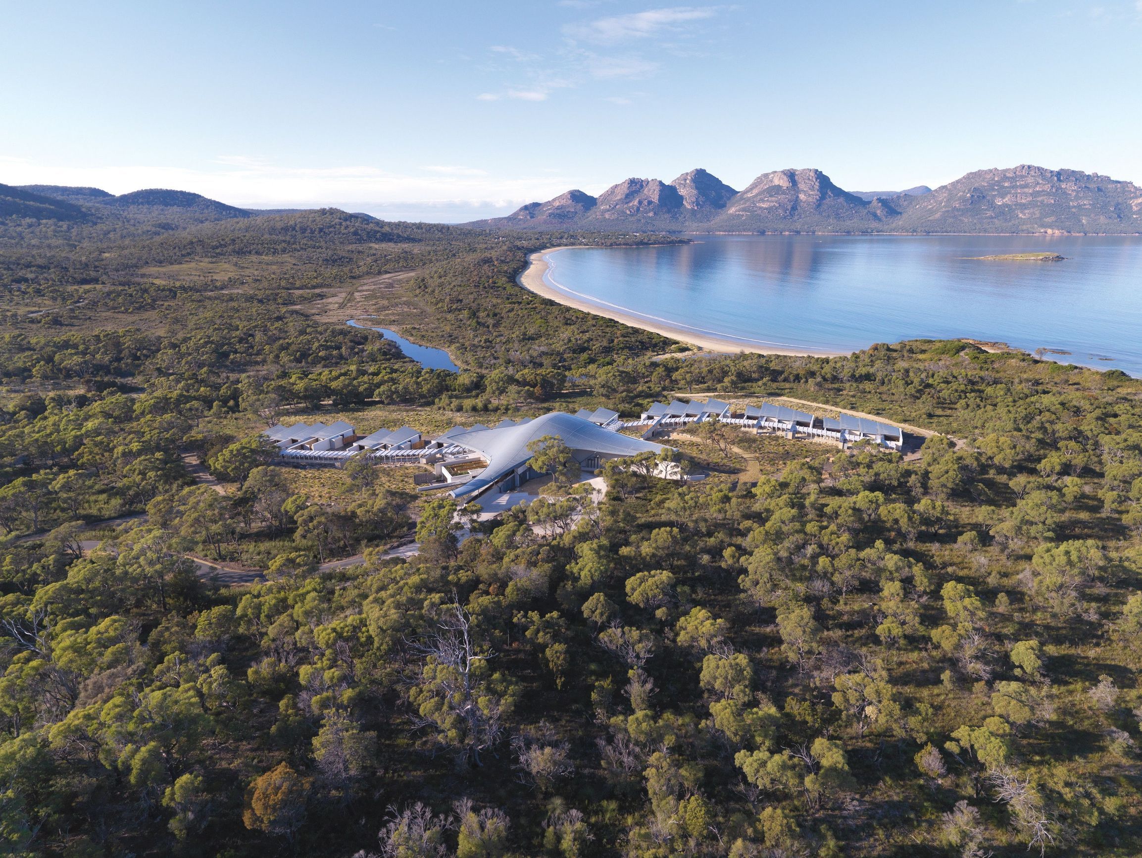 Aerial view of Saffire Freycinet resort surrounded by bushland with mountains and coastline behind