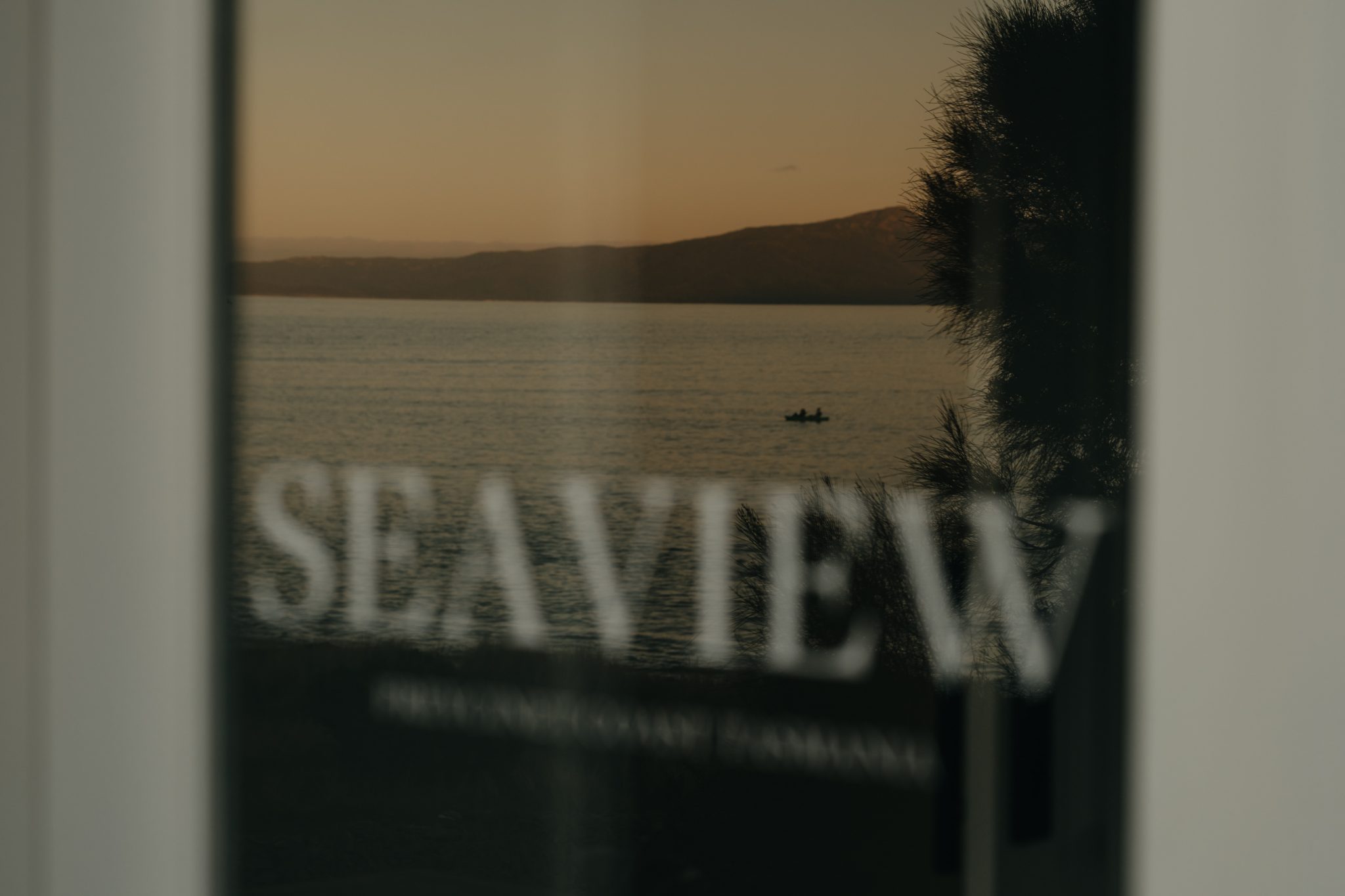 Seaview sign etched on glass with Great Oyster Bay and a small boat beyond
